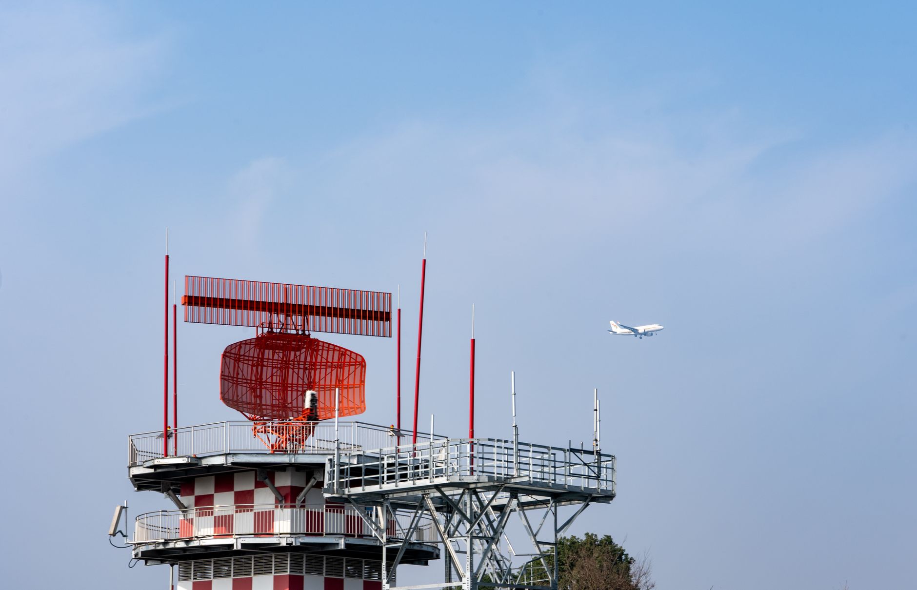 Airport radar tower with an aircraft overhead